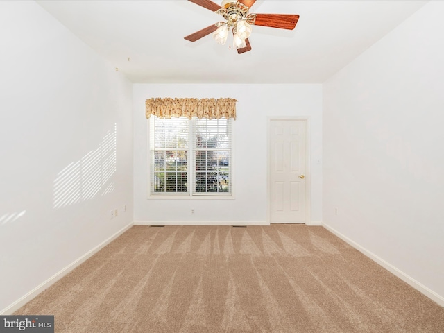 spare room with carpet floors, a ceiling fan, and baseboards