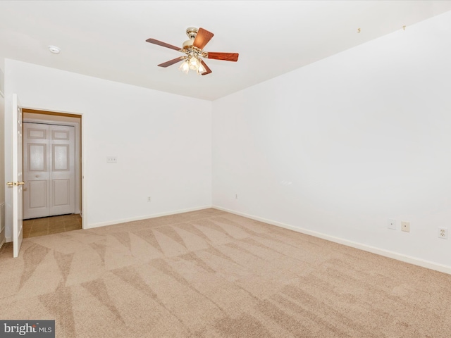 carpeted empty room featuring baseboards and a ceiling fan