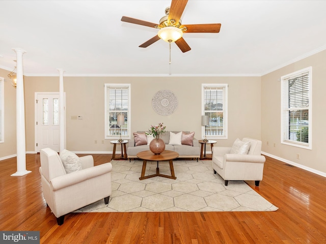 living area featuring ceiling fan, ornamental molding, light wood-style floors, and ornate columns