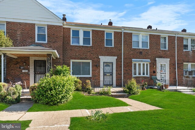 view of property with brick siding, a front lawn, a chimney, and cooling unit