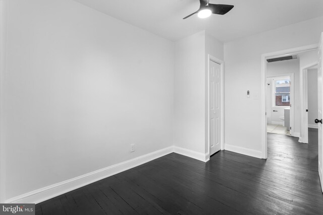 unfurnished bedroom featuring baseboards, dark wood-type flooring, a ceiling fan, and a closet
