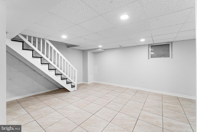 finished basement with stairs, recessed lighting, and a paneled ceiling