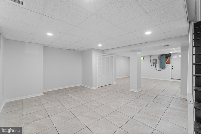 finished below grade area featuring electric panel, a paneled ceiling, recessed lighting, and baseboards