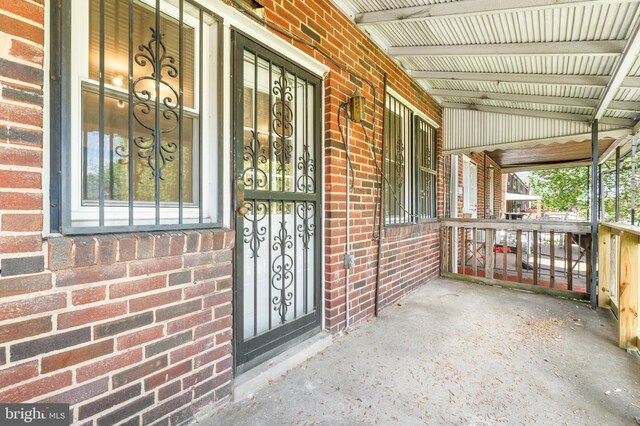 doorway to property with brick siding and a porch