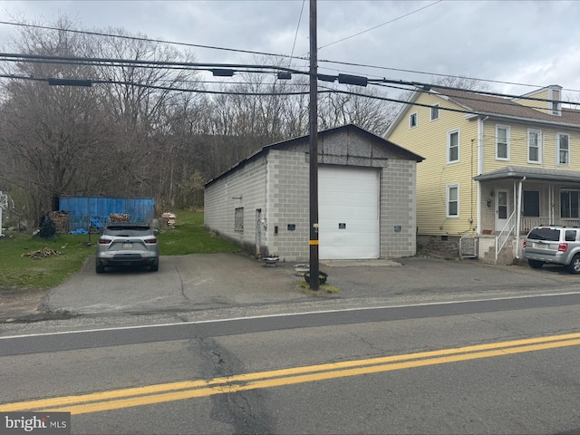 view of front of property with driveway, an outdoor structure, concrete block siding, and a detached garage