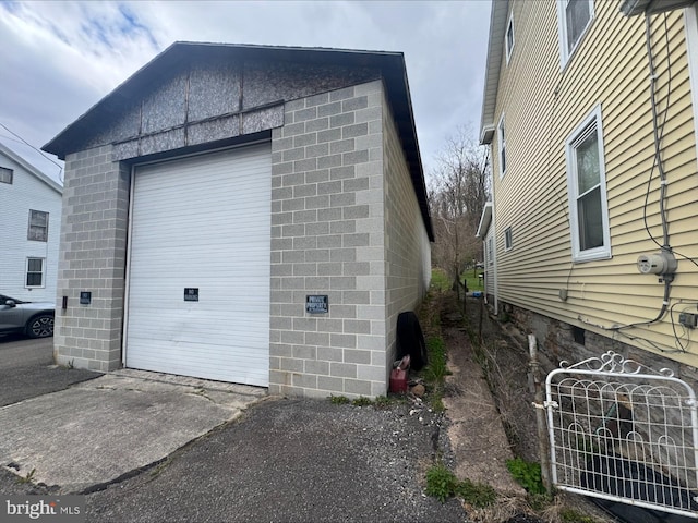 view of side of property with concrete block siding, an outbuilding, and driveway