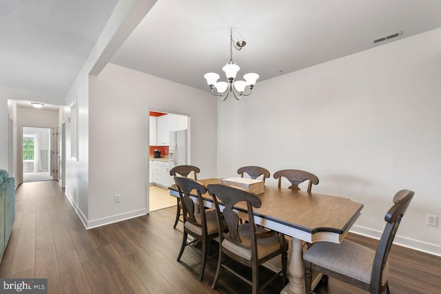 dining room with an inviting chandelier, baseboards, wood finished floors, and visible vents