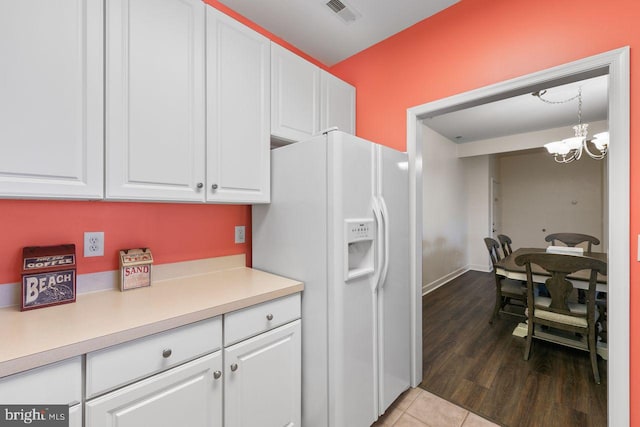 kitchen with visible vents, an inviting chandelier, light countertops, white cabinets, and white fridge with ice dispenser