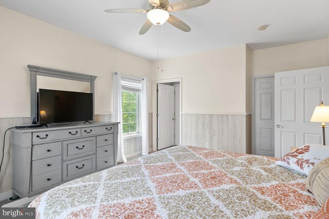 bedroom featuring a ceiling fan and wainscoting