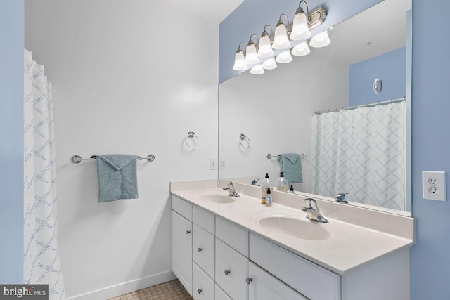 full bathroom with double vanity, baseboards, a sink, and tile patterned flooring
