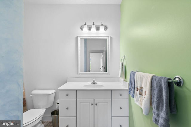 bathroom with vanity, baseboards, and toilet