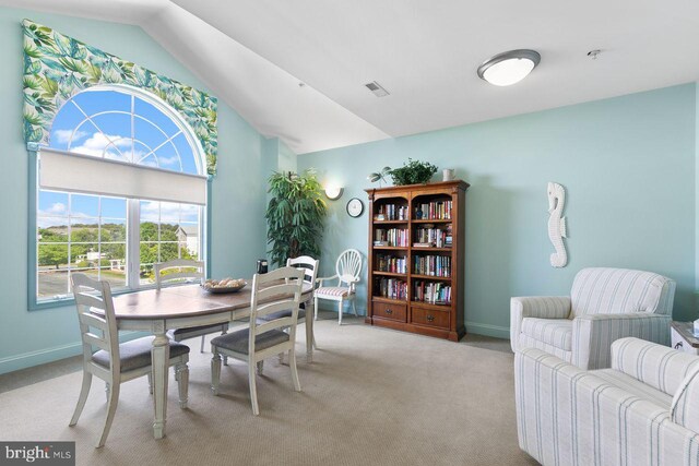 dining room with baseboards, vaulted ceiling, light carpet, and visible vents