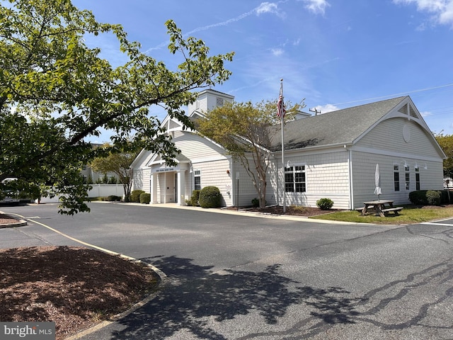 view of front of property with a shingled roof and fence