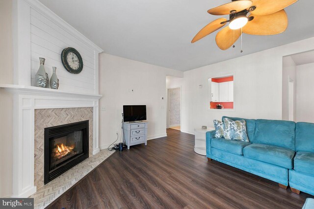 living room featuring a high end fireplace, baseboards, a ceiling fan, and dark wood-style flooring