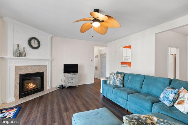 living room featuring baseboards, a fireplace, a ceiling fan, and wood finished floors