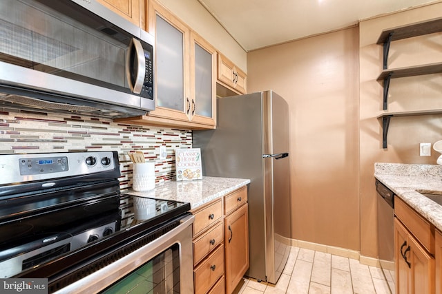 2639 Boston St Unit 203, Baltimore, MD 21224 - kitchen featuring tasteful backsplash, light stone countertops, glass insert cabinets, stainless steel appliances, and baseboards