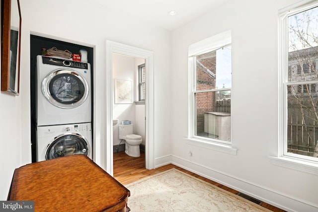 20-22 W Harvey St, Philadelphia, PA 19144 - clothes washing area featuring stacked washing machine and dryer, wood finished floors, healthy amount of natural light, and baseboards