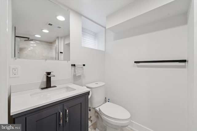 bathroom featuring toilet, vanity, and a shower