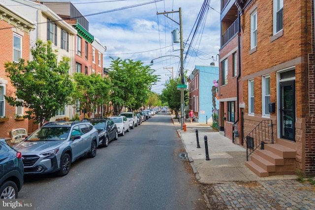 view of asphalt road featuring street lighting, sidewalks, entry steps, and curbs