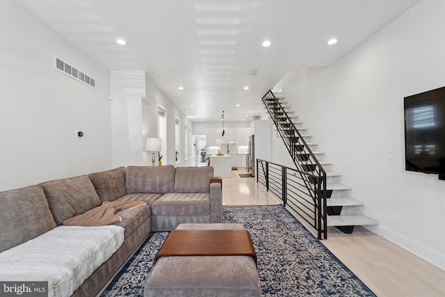 living room featuring light wood finished floors, stairway, recessed lighting, and baseboards