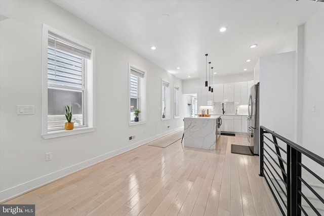 unfurnished living room with baseboards, recessed lighting, and light wood-style flooring