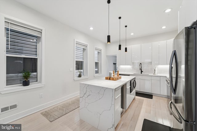 kitchen with stainless steel appliances, white cabinets, a kitchen island, modern cabinets, and a sink
