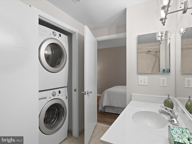 350 G St SW Unit N407, Washington, DC 20024 - laundry area with stacked washer and clothes dryer, a sink, laundry area, and light tile patterned flooring