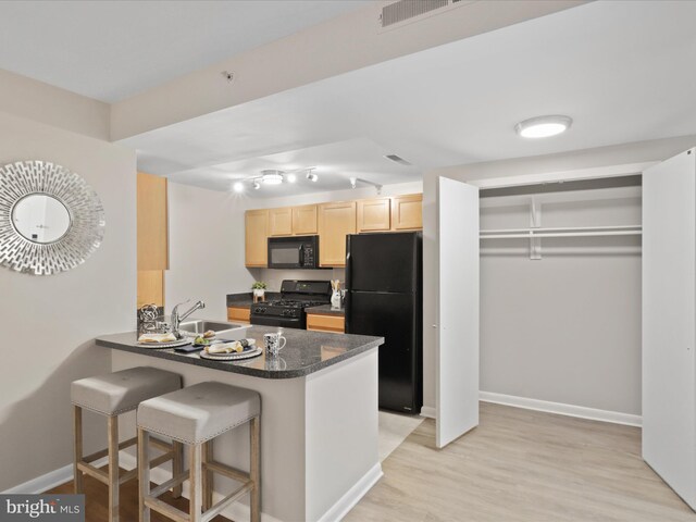 350 G St SW Unit N407, Washington, DC 20024 - kitchen with light brown cabinets, a sink, black appliances, light wood-style floors, and a peninsula