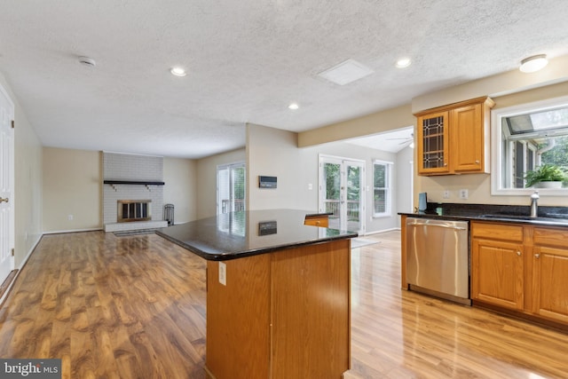 15915 Marlington Dr, Dumfries, VA 22025 - kitchen featuring stainless steel dishwasher, a sink, a textured ceiling, light wood-style flooring, and open floor plan