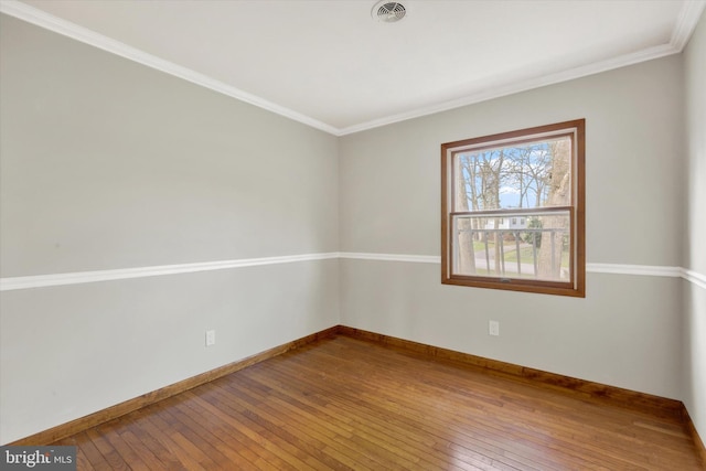 unfurnished room featuring baseboards, ornamental molding, hardwood / wood-style floors, and visible vents