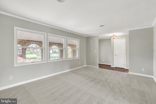 carpeted spare room featuring baseboards and crown molding
