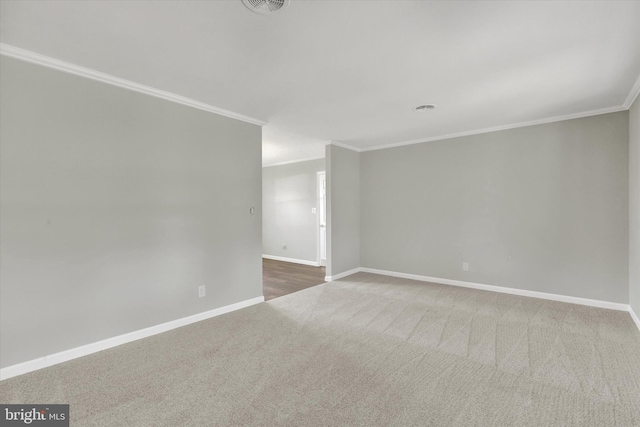 spare room featuring carpet floors, crown molding, visible vents, and baseboards