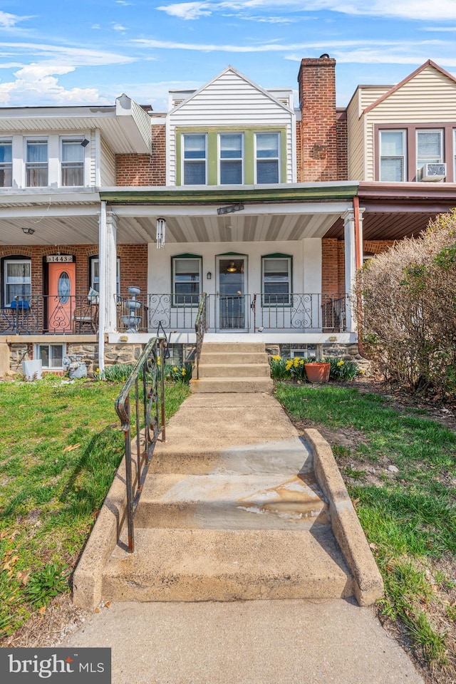 townhome / multi-family property with brick siding, a porch, and a front yard