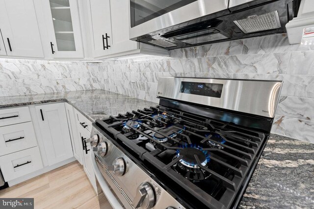 kitchen with appliances with stainless steel finishes, stone counters, and white cabinets
