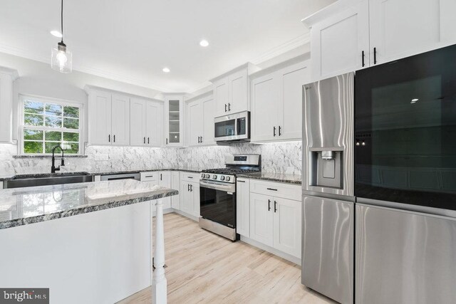 kitchen featuring stainless steel appliances, a sink, dark stone countertops, tasteful backsplash, and crown molding