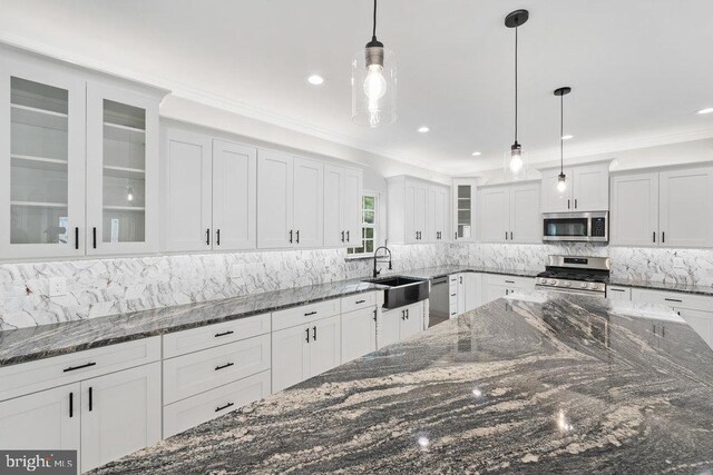 kitchen featuring appliances with stainless steel finishes, white cabinets, decorative backsplash, decorative light fixtures, and ornamental molding
