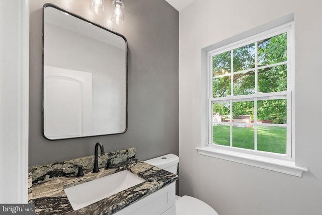 bathroom featuring healthy amount of natural light, toilet, and vanity
