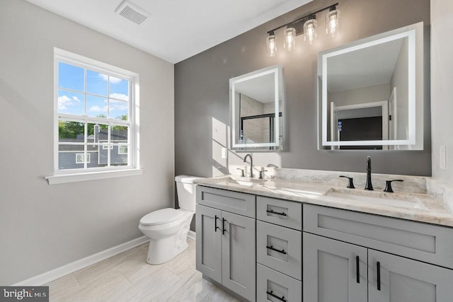bathroom with baseboards, toilet, double vanity, and a shower
