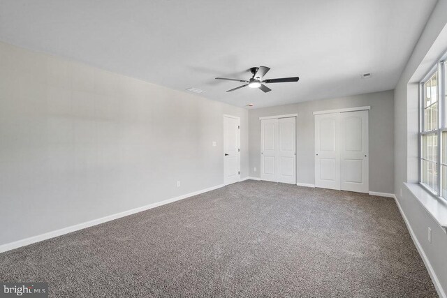 unfurnished bedroom with multiple closets, carpet floors, baseboards, and ceiling fan