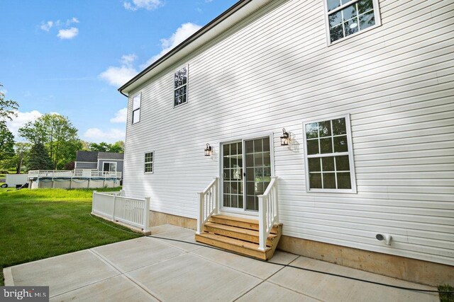 back of house with entry steps, a yard, and a patio area