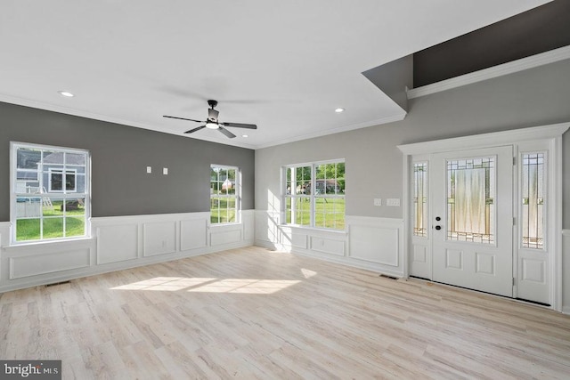 foyer featuring a ceiling fan, ornamental molding, a decorative wall, a wainscoted wall, and wood finished floors