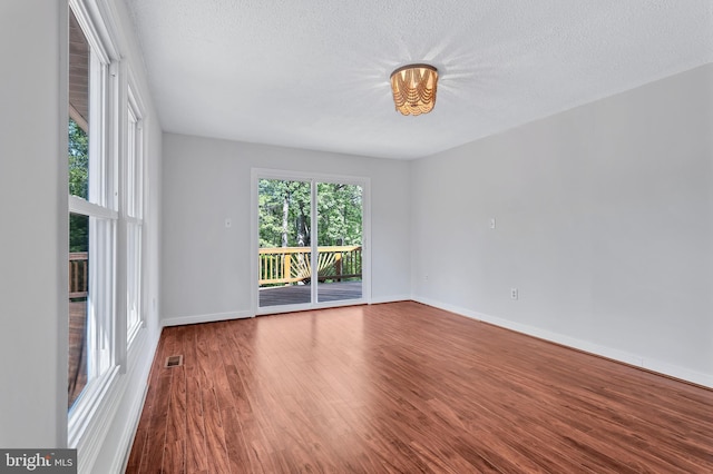 unfurnished room with baseboards, visible vents, and wood finished floors