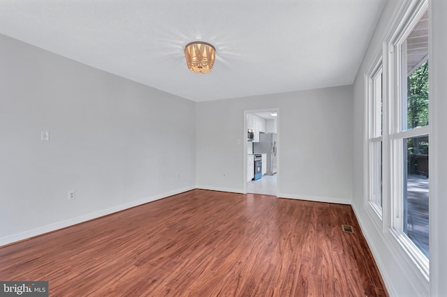 spare room featuring baseboards, visible vents, and wood finished floors