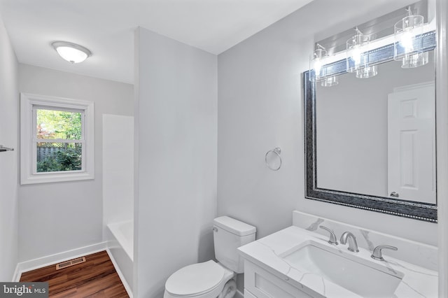 bathroom with vanity, toilet, visible vents, baseboards, and wood finished floors