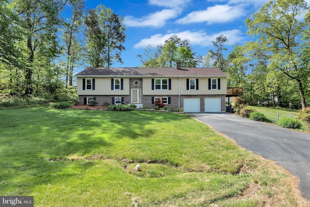 bi-level home with driveway, a chimney, a front yard, an attached garage, and brick siding