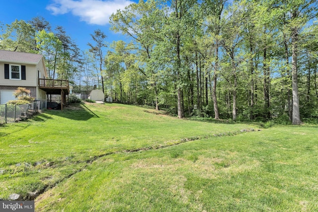 view of yard with fence, an outbuilding, a storage shed, a garage, and a wooden deck