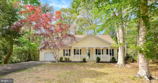 view of front of property featuring a porch, an attached garage, driveway, and a front yard