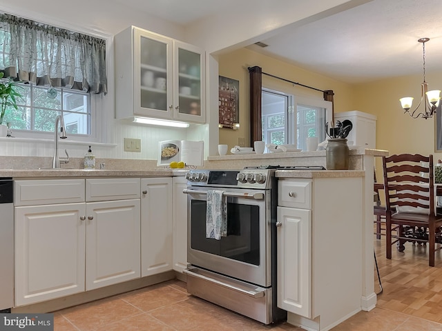 kitchen featuring stainless steel range with gas stovetop, a peninsula, a notable chandelier, and white cabinetry