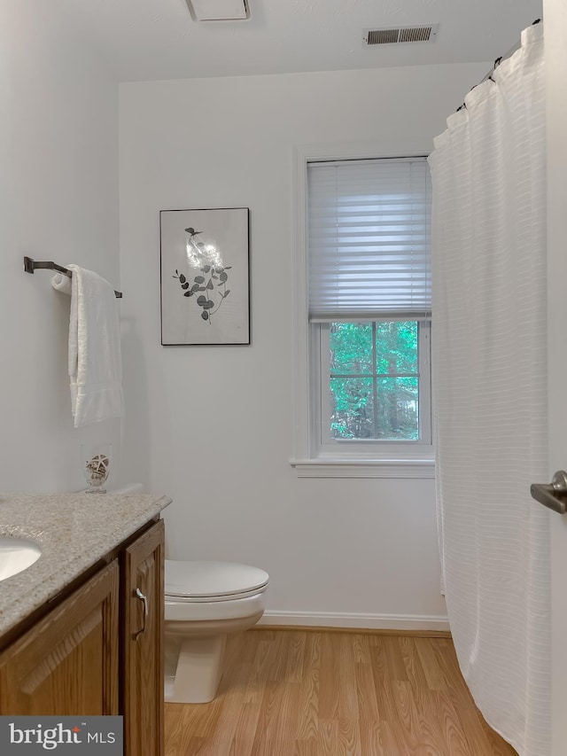 bathroom with vanity, toilet, baseboards, wood finished floors, and visible vents