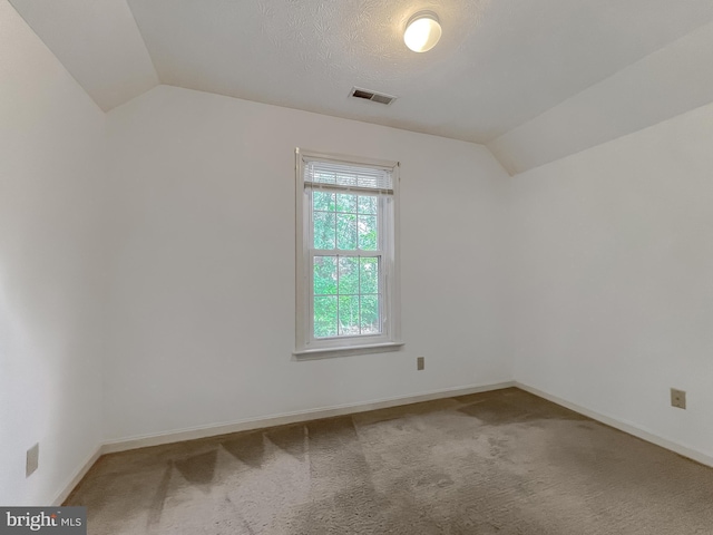 empty room featuring baseboards, visible vents, carpet flooring, and lofted ceiling